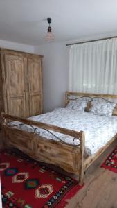 1 dormitorio con cama de madera y cabecero de madera en La Marginea Pădurii, en Marginea Pădurii