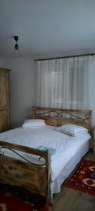 Un dormitorio con una cama de madera con sábanas blancas y una ventana. en La Marginea Pădurii, en Marginea Pădurii