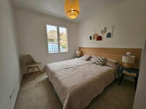 a bedroom with a bed and a chair and a window at Appartement Chez Emma, le luxe en Bord de Mer by Monarca in Saint-Florent