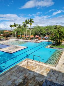 ein großer Pool mit blauem Wasser und Palmen in der Unterkunft Portal de Gravatá para até 6 pessoas - Térreo in Gravatá