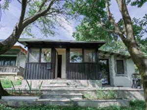 una vecchia casa con portico e alberi di Casa din sat a Marginea Pădurii
