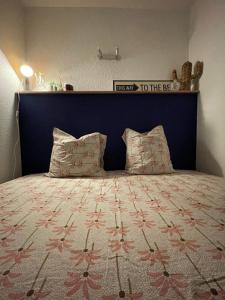 Bett mit blauem Kopfteil und 2 Kissen in der Unterkunft Capstay studio Barcarès in Le Barcarès