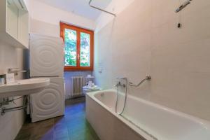 een witte badkamer met een bad en een wastafel bij Bella Menaggio Terrazzo in Menaggio +7 foto's