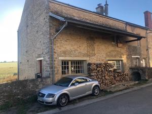 a car parked in front of a brick building at Les Iris in Fontenay-près-Vézelay