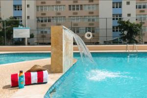 a pool with a water fountain in a building at Apartamento con vistas al mar Isla Verde Puerto Rico in San Juan