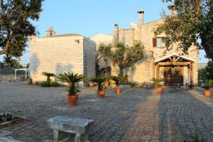 a brick building with a stone courtyard with potted plants at Masseria Tolla in Ostuni