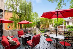 a patio with red chairs and tables and umbrellas at DuPont Mansion Bed & Breakfast in Louisville