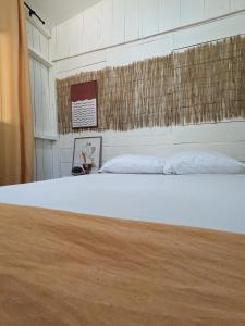 a bedroom with a white bed with a wooden floor at Hostel Los Pargos in Río Sequito