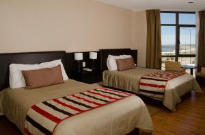 a hotel room with two beds and a window at Hotel y Casino Del Río - Las Grutas in Las Grutas