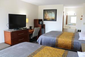 Una habitación de hotel con dos camas y un escritorio con televisión. en Budget inn, en Greenville