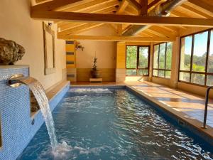 a pool with a waterfall in a house at Apartamentos La Fabrica in Villaluenga de la Vega