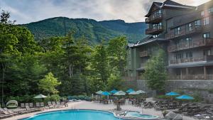a view of a hotel with a pool and tables and chairs at 378 Lodge At Spruce Peak Ski In Ski In Ski Out King Studio By Stowe Mountain Rentals in Stowe