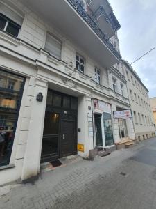 a white building with a black door on a street at Power Nap by Harmonia 24h self check-in in Poznań