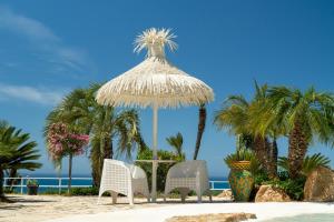 two chairs and a straw umbrella on the beach at Casa Vacanze Verdemare con Piscina in Ribera