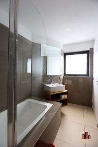 a white bathroom with a tub and a sink at Riviera Residence Luxury by Cozy in Accra