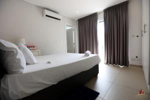 a bedroom with a large white bed and a window at Riviera Residence Luxury by Cozy in Accra +33 photos