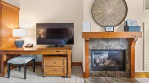 a room with a desk and a fireplace and a television at 145 Lodge At Spruce Peak Ski In Ski In Ski Out King Studio By Stowe Mountain Rentals in Stowe