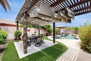 a patio with a table and chairs under a pergola at Deerbrook Manor Permit# 67085 in La Quinta