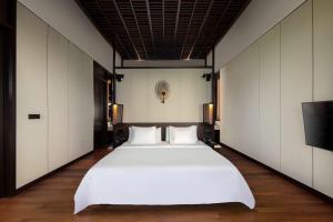 a large white bed in a room with a tv at Radisson Blu Bali Uluwatu in Uluwatu