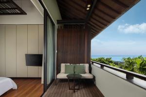 a room with a balcony with a bed and a television at Radisson Blu Bali Uluwatu in Uluwatu