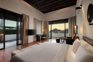 a bedroom with a large bed and a living room at Radisson Blu Bali Uluwatu in Uluwatu