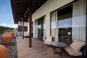 a balcony with chairs and a table and some windows at Radisson Blu Bali Uluwatu in Uluwatu
