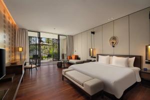 a bedroom with a large white bed and a couch at Radisson Blu Bali Uluwatu in Uluwatu