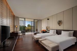a bedroom with a large white bed and a living room at Radisson Blu Bali Uluwatu in Uluwatu