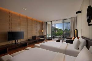 a hotel room with two beds and a flat screen tv at Radisson Blu Bali Uluwatu in Uluwatu