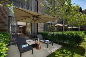 a patio with two chairs and an umbrella at Radisson Blu Bali Uluwatu in Uluwatu