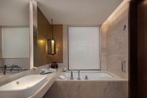 a bathroom with a tub and a sink and a mirror at Radisson Blu Bali Uluwatu in Uluwatu
