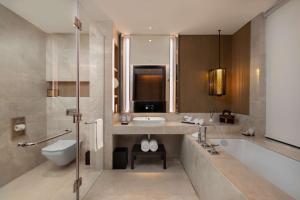 a bathroom with a tub and a sink and a toilet at Radisson Blu Bali Uluwatu in Uluwatu