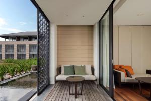 a balcony with a table and chairs and a pool at Radisson Blu Bali Uluwatu in Uluwatu