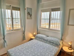 Un dormitorio con una cama y dos ventanas. en Apartamento Mar Menor - Beachfront apartment with large patio - under new management since July 2024 - Licence No VVMU2814-1, en Cartagena