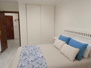 a bedroom with a bed with blue and white pillows at Preto do Mar in Corcubión