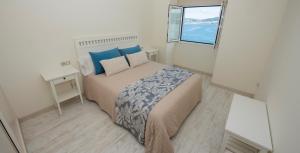 a bedroom with a bed with blue pillows and a window at Preto do Mar in Corcubión