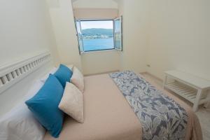 a bedroom with a bed with blue pillows and a window at Preto do Mar in Corcubión +12 photos