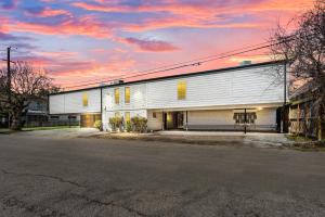 a large white building with a sunset in the background at Cute and Stylish 1BR Apt with Pool & Free Park in Houston