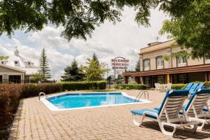 two chairs and a swimming pool in front of a building at Hôtel St-Bernard in St-Bernard de Lacolle