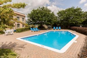 a swimming pool with blue chairs and a house at Hôtel St-Bernard in St-Bernard de Lacolle
