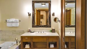 a bathroom with two sinks and a tub and a mirror at 1234 Lodge At Spruce Peak Ski In Ski In Ski Out King Studio By Stowe Mountain Rentals in Stowe +10 photos