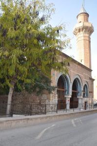 un bâtiment avec une tour d'horloge sur le côté d'une rue dans l'établissement Mevlana Palace, à Konya