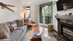 Una sala de estar con un sofá y una chimenea. en 1302 Lodge At Spruce Peak Ski In Ski Out Two Bedroom By Stowe Mountain Rentals, en Stowe
