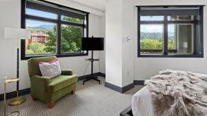 Un dormitorio con una cama y una silla y ventanas. en 1302 Lodge At Spruce Peak Ski In Ski Out Two Bedroom By Stowe Mountain Rentals, en Stowe 15 fotos más