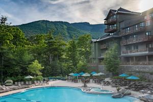 un hotel con piscina con sillas y sombrillas en 1302 Lodge At Spruce Peak Ski In Ski Out Two Bedroom By Stowe Mountain Rentals, en Stowe