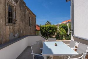 - Balcón con mesa blanca y sillas en Apartments with parking space Vir - 22682, en Vir