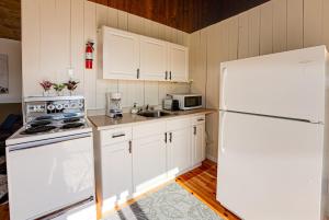 Una cocina con gabinetes blancos y un refrigerador blanco. en Love of Lake Cecebe #7 - Maijac Resort & Marina, en Burks Falls