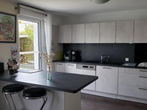 a kitchen with white cabinets and a black counter top at Maison cosy à Guérande, proche cité médiévale, avec jardin, terrasse, fibre et home cinéma. - FR-1-306-970 in Guérande +10 photos