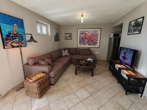 a living room with a couch and a tv at Holiday house with a swimming pool Stanici, Omis - 22998 in Omiš