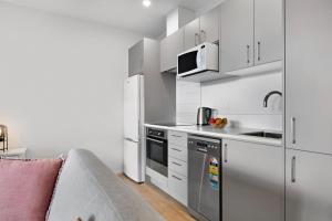 a kitchen with white cabinets and a sink and a couch at Haeata View in Queenstown